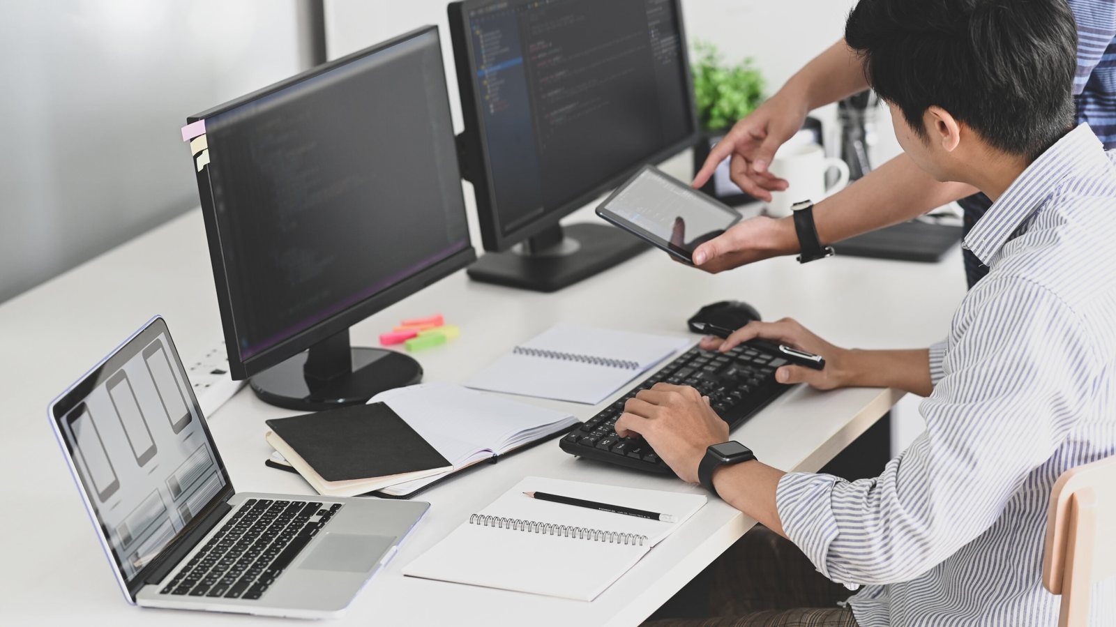 IT technician working at a computer with multiple monitors